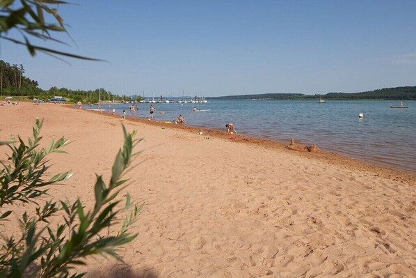 Ein Strand mit klarem Wasser, Booten und einem sandigen Ufer.