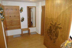 Ein Zimmer mit einem Holzkleiderschrank, einer Sitzbank und einer Tür mit einem Stierkopf-Schnitzwerk.