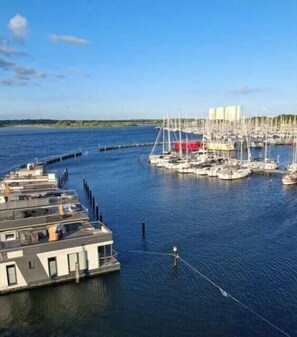 A marina with multiple boats docked, a floating structure with a roof, and a clear blue sky. - Apartment with 1 bedroom (Fehmarn\/ Burgtiefe)