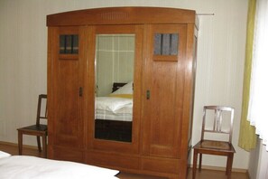 Una stanza con un'armadio in legno, un letto, una sedia e una finestra con tende.