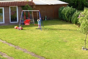 A residential property with a fenced yard, a swing set, and a small tree. - Holiday apartment - Bachmann (Hagenburg)