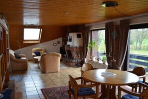 Ein gemütliches Wohnzimmer mit Kamin, Esstisch und Fernseher.