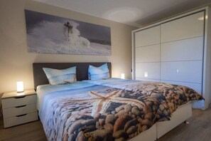 Ein Schlafzimmer mit einem Bett, Nachttischen, einem großen Gemälde und einem Kleiderschrank.