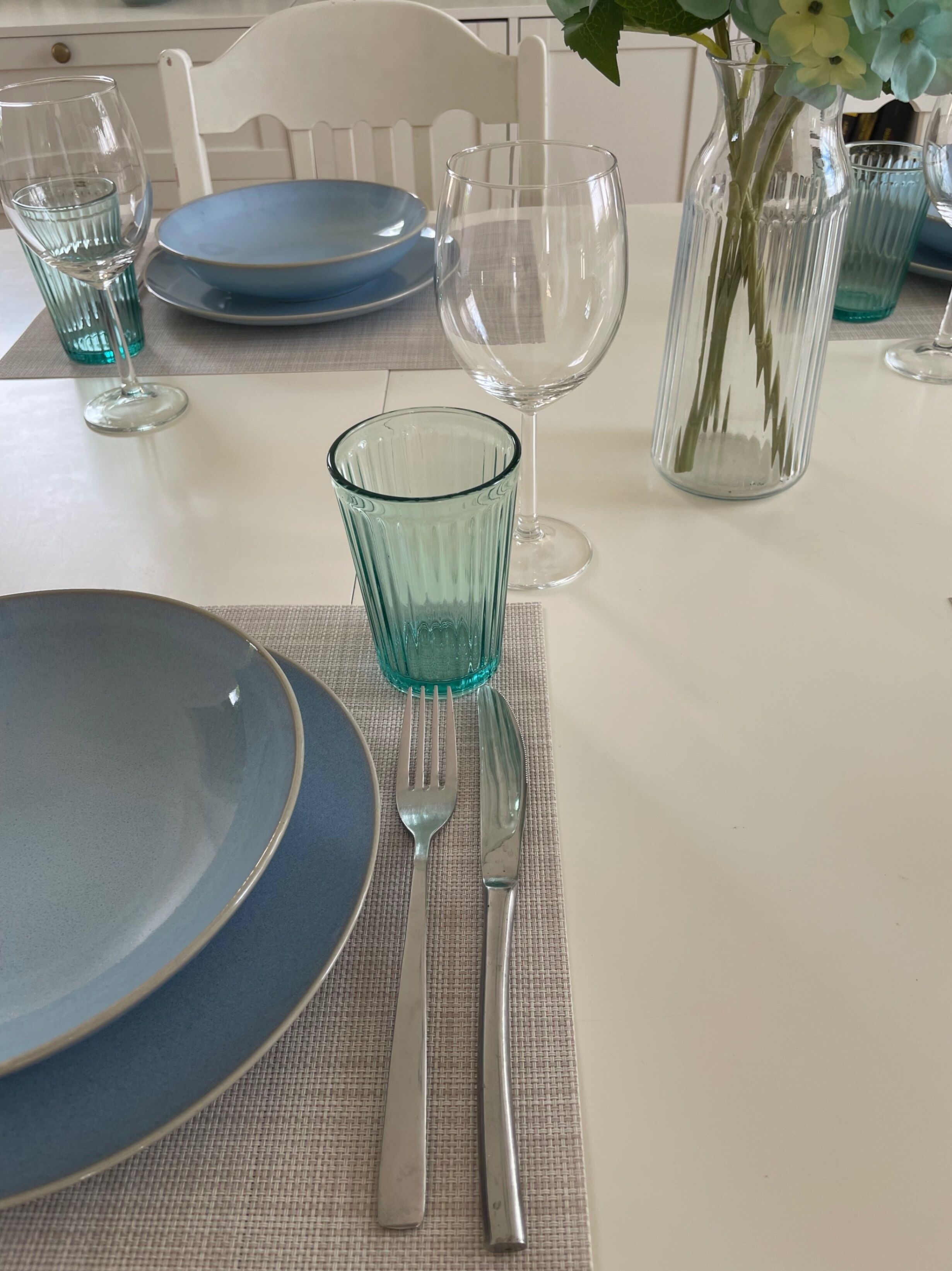 A dining table set with plates, cutlery, and glasses.
