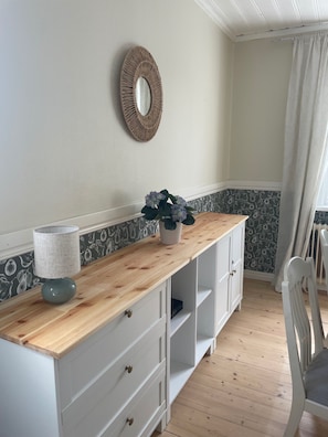 Une pièce avec un bureau en bois, un miroir, une plante en pot et une chaise.