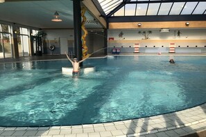 Ein hallenbad mit klarem Wasser, einer zentralen Säule und einer darin schwimmenden Person.