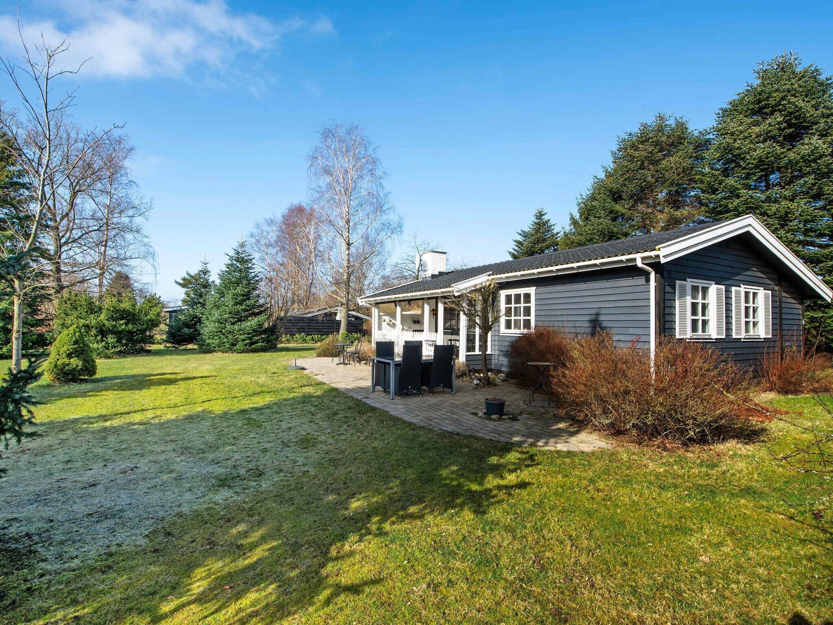 Ett hus med en täckt uteplats, en gräsmatta och träd runt omkring.
