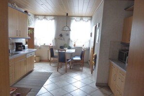 Eine Küche mit Holzschränken, einem Esstisch mit Stühlen und einer Pendelleuchte.