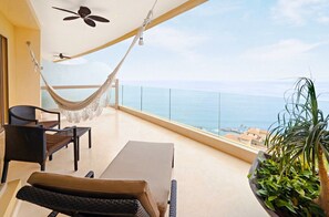 Ein Balkon mit einer Hängematte, einem Tisch, Stühlen und einem Blumentopf.