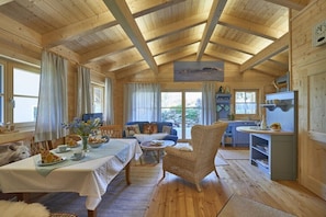 A cozy cabin interior with a dining area, a sofa, a chair, and a kitchen area. - Log cabin "Bergheimat" (Wegscheid)