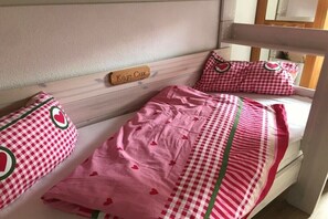 Ein Einzelbett mit karierter Bettdecke und Kissen, ein Holz-Kopfteil und eine Namensschild.