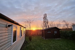 Ein Wohngebiet mit einem Haus, einem kleinen Gartenhaus und einer Rasenfläche im Abendlicht.
