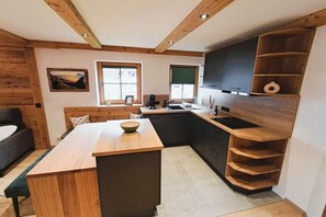 Eine kompakte Küche mit Holzschränken, einer zentralen Kücheninsel und einer eingebauten Regaleinheit.