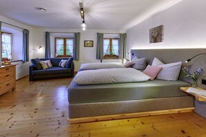 Ein Schlafzimmer mit Bett, Sofa, Kommode und einem Fenster mit Vorhängen.