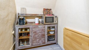 Una kitchenette equipada con microondas, cafetera y un pequeño armario con vajilla.