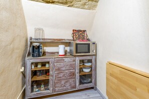 A kitchenette with a microwave, coffee maker, and a small cabinet with dishes.