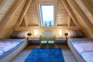 Ein gemütliches Schlafzimmer im Dachgeschoss mit zwei Betten, einem Fenster und einer Heizung.