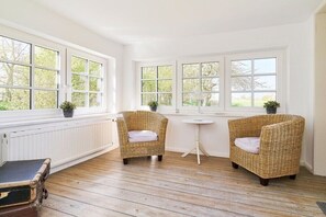 Ein Zimmer mit zwei Korbstühlen, einem kleinen runden Tisch und einer Heizung.