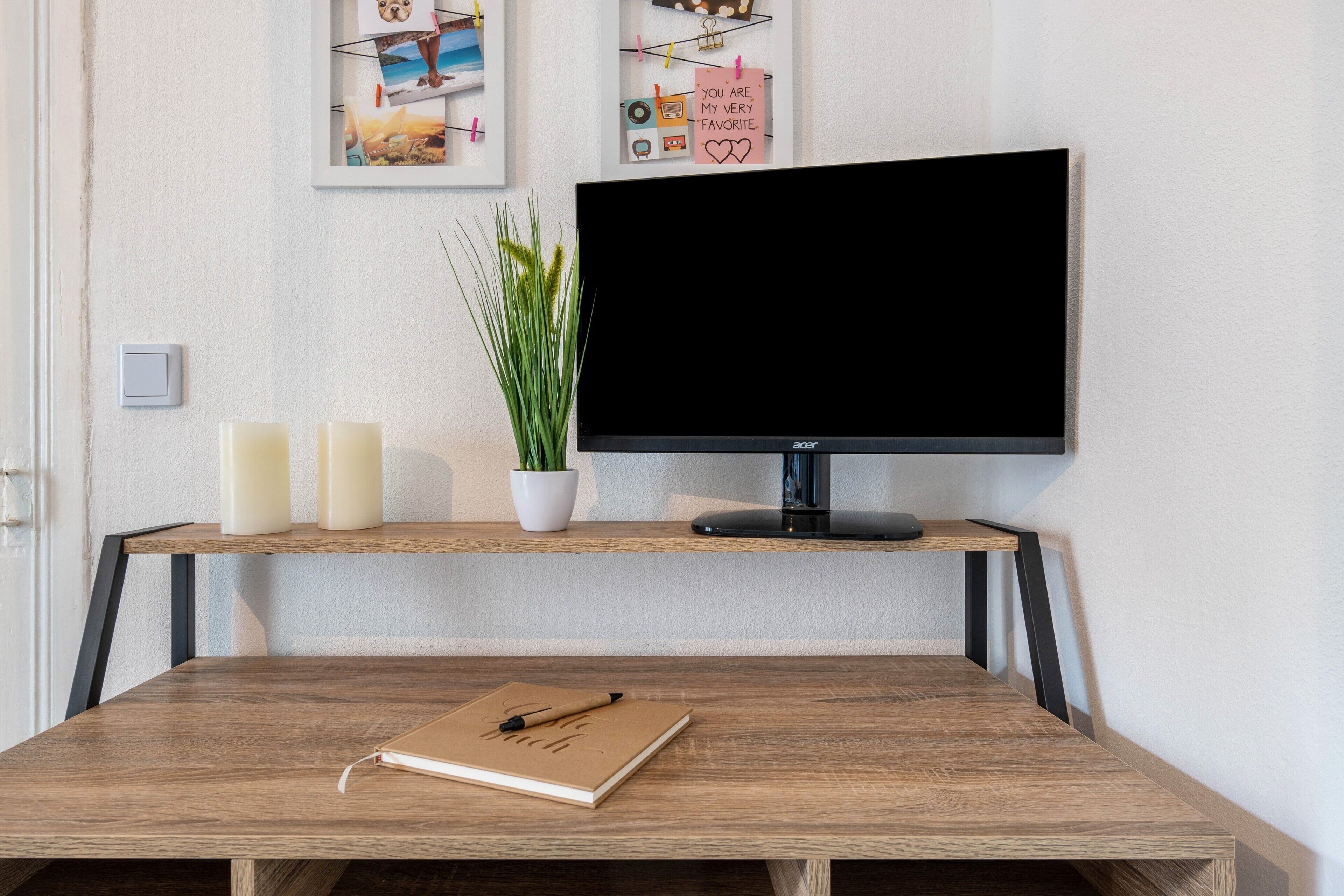 Een bureau met een notitieboekje, een pen, een plant in pot en kaarsen.