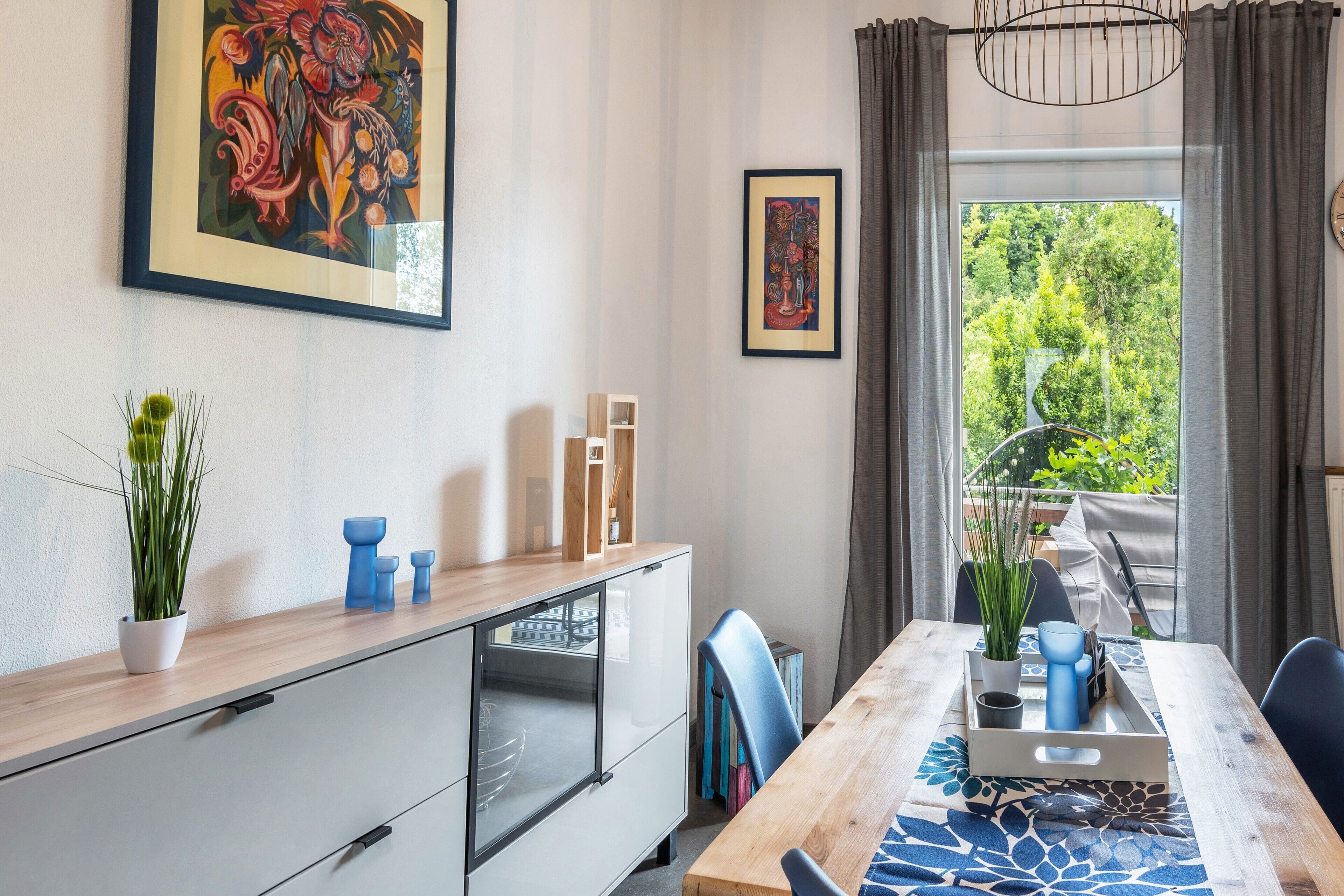 Een moderne eetruimte met een houten tafel, stoelen en uitzicht op groen buiten.