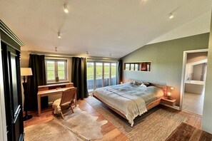 A bedroom with a bed, desk, chair, and a view of the outdoors. - Penthouse House Hemingway (Rosenhagen)