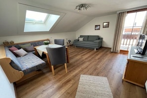 Un espacio habitable tipo loft con tragaluces, un sofá, una mesa de comedor y un televisor.