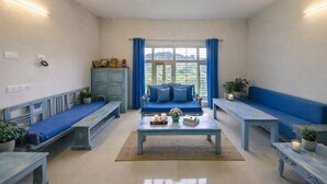 A room with a blue sofa, a coffee table, and benches along the walls. - Sky Mount Villa (Mount Abu)