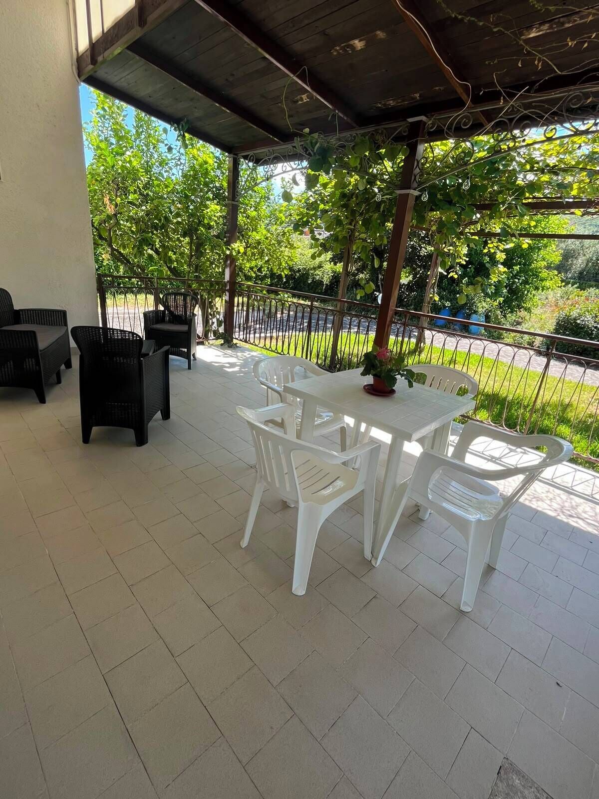 Un patio cubierto con mobiliario exterior, una mesa y sillas.