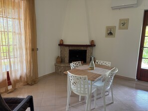Ein Essbereich mit Kamin, weißen Stühlen und einem Tisch.