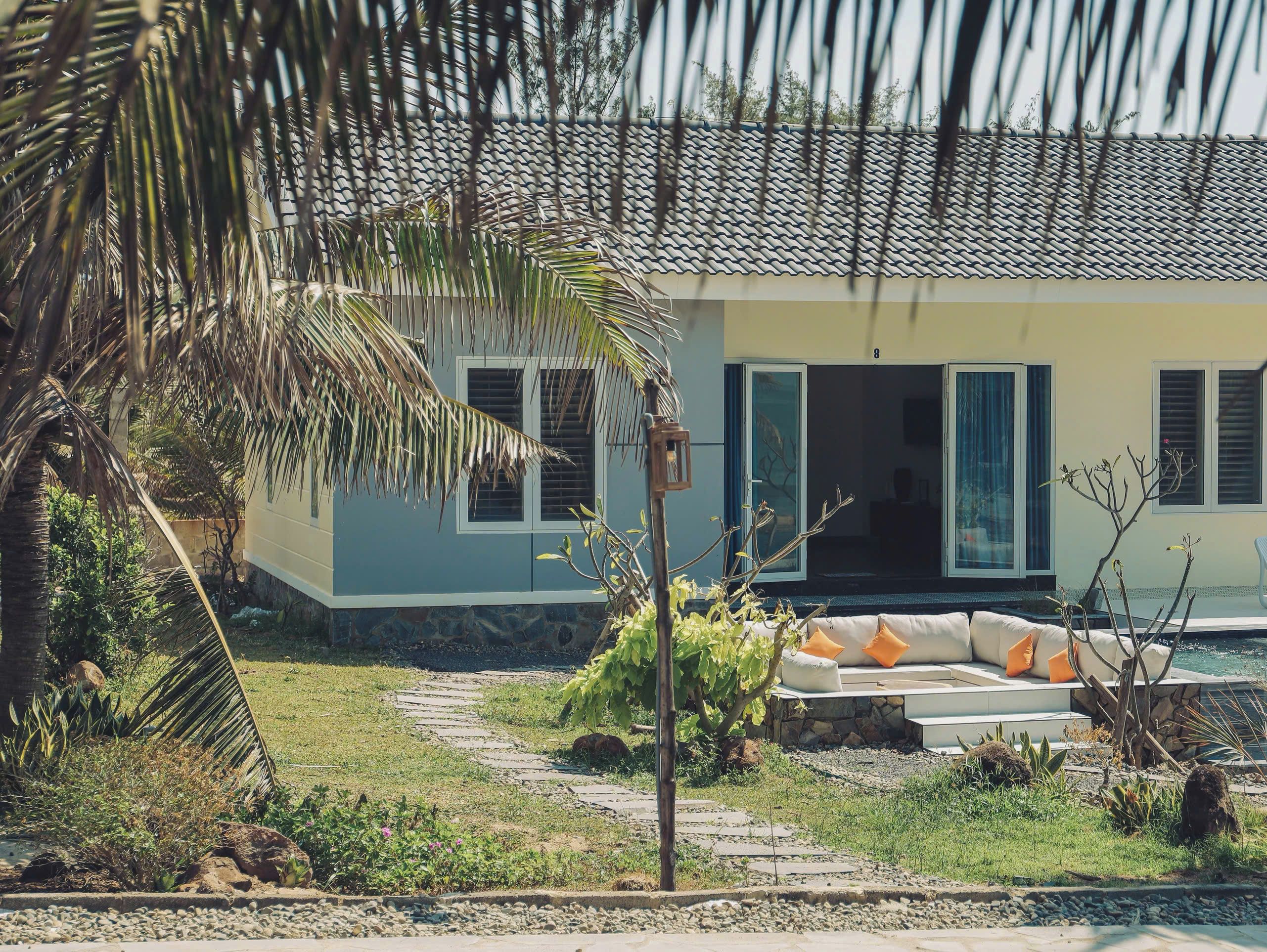A house with a stone pathway leading to a seating area with cushions.