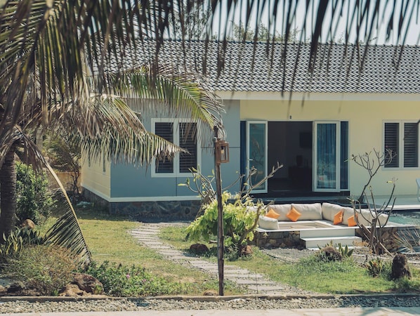 Una casa con un camino de piedra que lleva a un área de descanso con cojines.
