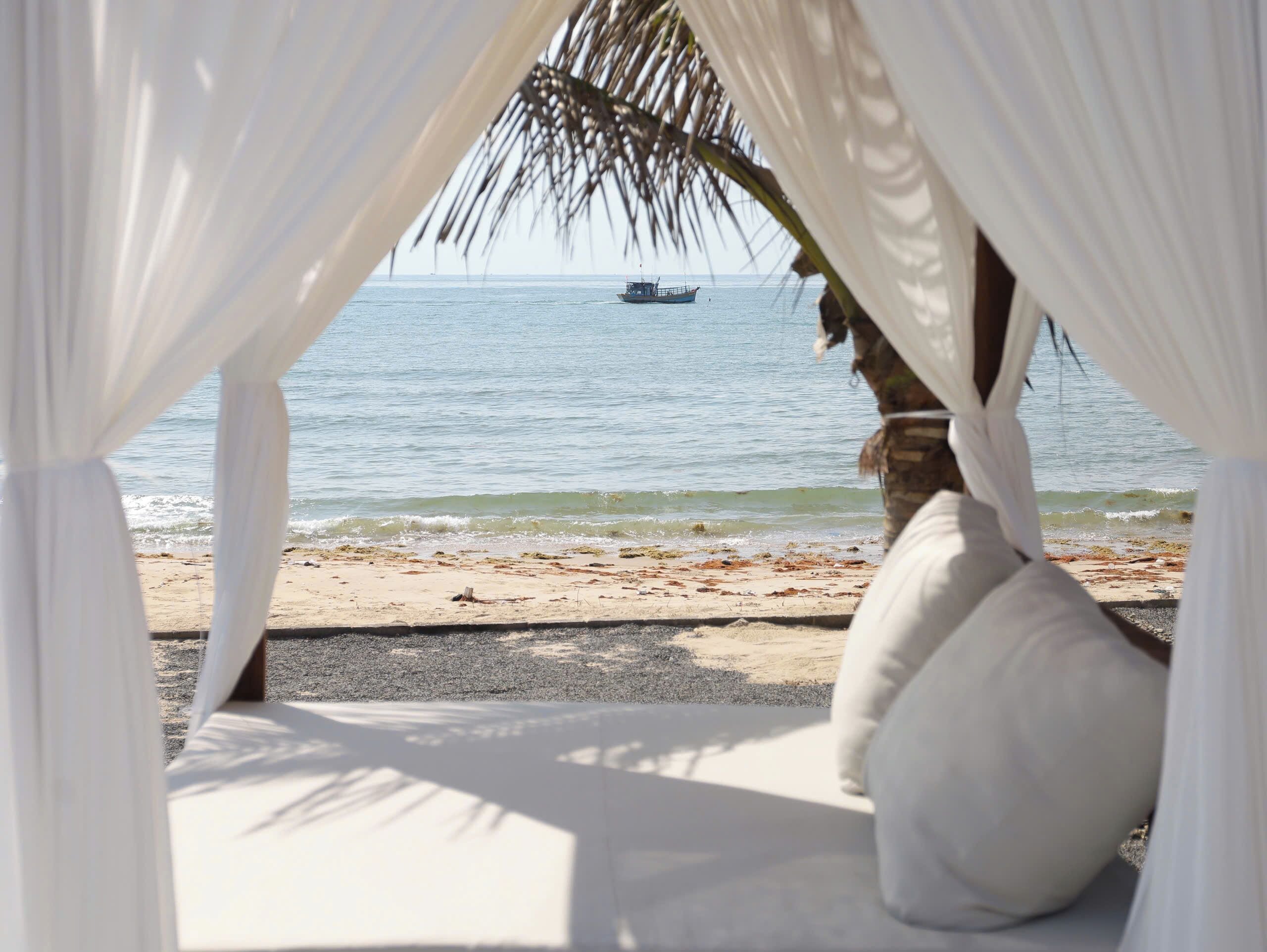A beach view from a covered area with a boat in the distance.