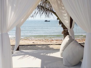 A beach view from a covered area with a boat in the distance.