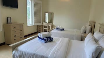 A hotel room with two beds, a dresser, a chair, a desk, and a television.