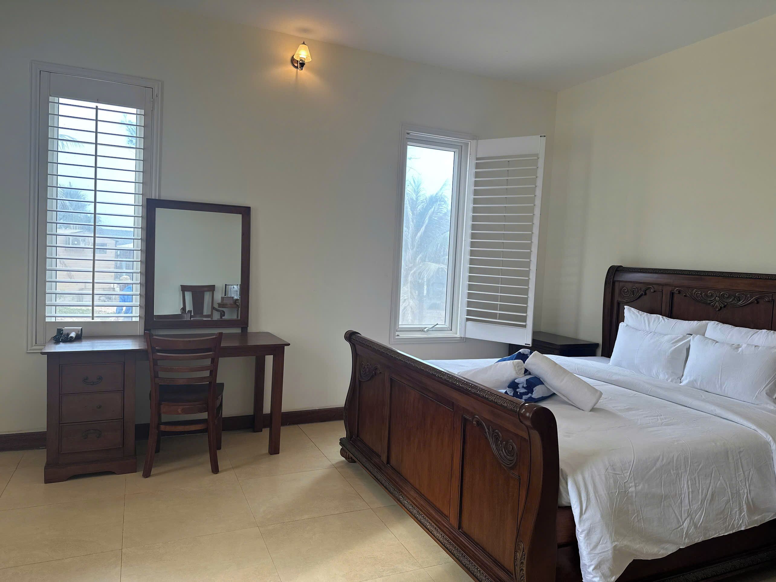 Un dormitorio con cama de madera, un escritorio, una silla y un espejo.