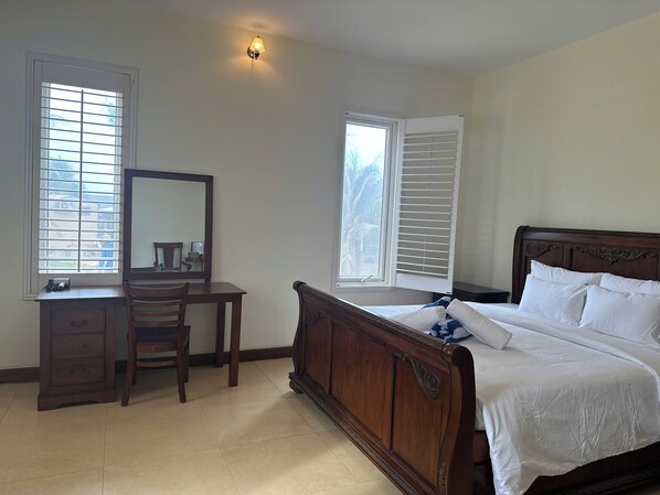A bedroom with a wooden bed, a desk, a chair, and a mirror.
