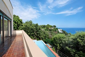 Ein modernes Gebäude mit Schwimmbad, großen Fenstern und Blick auf Meer und Grünflächen.