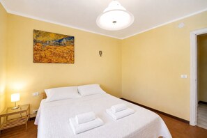 Ein Hotelzimmer mit Bett, einem Gemälde, einer Nachttischlampe und einer Tür.