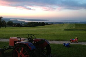 Ein Traktor auf einem grünen Feld mit Sonnenuntergang im Hintergrund.