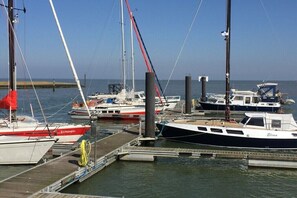 Ein Yachthafen mit vertäuten Booten, darunter ein rot-weißes Boot namens 'Eckstein' und ein schwarzes Boot namens 'Elina'.