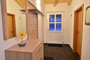 Ein Flur mit einem Holzkommode, einem Spiegel, einer Tür mit Fenster und einem gerahmten Bild an der Wand.