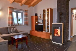 Ein Wohnzimmer mit Sofa, Couchtisch, Fernsehschrank und Kamin.