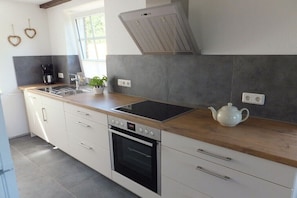 Eine moderne Küche mit integriertem Backofen, Kochfeld und Wasserkocher auf der Arbeitsfläche.