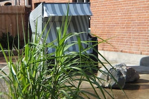 Ein Backsteinhaus mit Streifenveranda, einem Holzzaun und Pflanzen im Vordergrund.