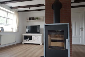 Ein Wohnzimmer mit Kamin, Fernseher und weißen Möbeln.