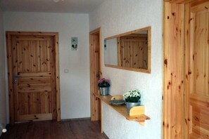 Ein Flur mit Holztüren, einem Spiegel und einem Regal mit Topfpflanzen.