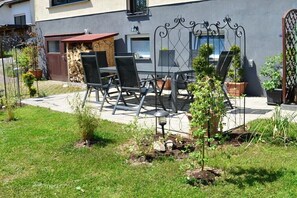Eine Terrasse mit Gartenmöbeln, einem Metallzaun und Blumentöpfen.