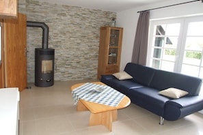 Ein Wohnzimmer mit einer Couch, einem Holztisch, einem Kamin, einem Schrank und einem Fenster.