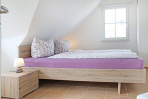 Ein Schlafzimmer mit einem Holzbett, einem Nachttisch, einer Lampe und einem Fenster.