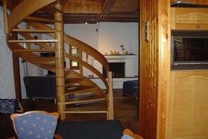 Eine Wendeltreppe in einem Holzinnenraum mit Kamin und Fernseher.